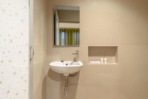 a bathroom with a sink and a mirror at Capital O 1585 Ring Road Residence in Medan
