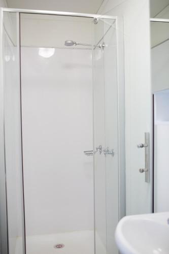 a shower with a glass door next to a sink at Capricorn Village in Newman