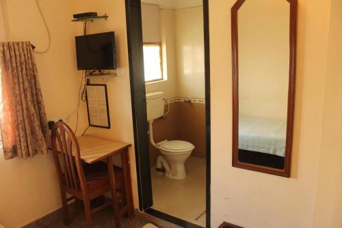 a bathroom with a toilet and a table and a mirror at YWCA International Centre in Mumbai