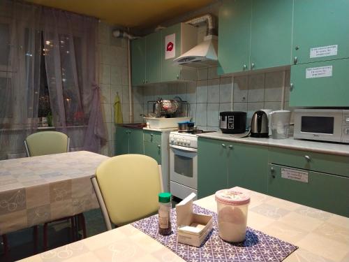 モスクワにあるХостелы Рус Юго-Западнаяのキッチン(緑のキャビネット、ドリンクを楽しめるテーブル付)