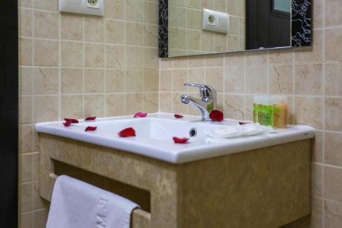 een wastafel met rode rozenblaadjes erop bij Hôtel Suite Martil in Martil