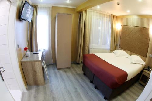 a bedroom with a bed and a desk and a television at Hotel Phenix in Brussels