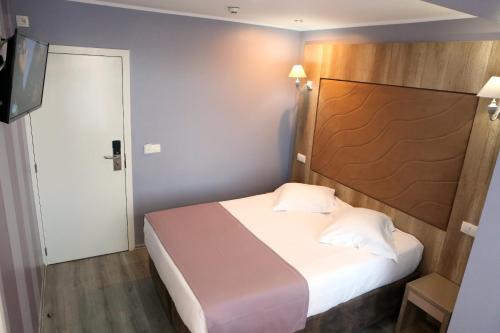 a small bedroom with a bed and a television at Hotel Phenix in Brussels
