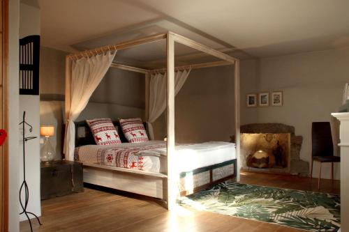um quarto com uma cama de dossel e uma lareira em L'Alcôve d'Amédée V em Yvoire