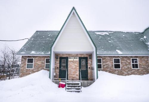 a brick house with snow in front of it at Yotei Townhouse - 2 bedrooms with covered BBQ deck in Niseko