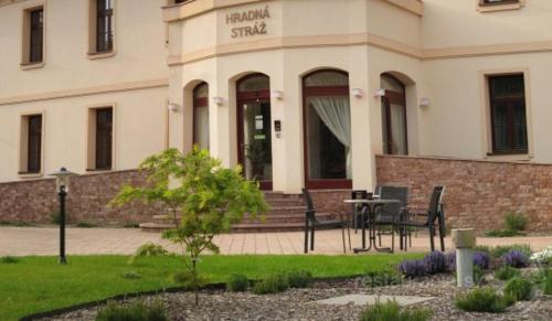 a building with a table and chairs in front of it at Hradná stráž Hotel&Apartments s privátnym wellness in Topoľčianky