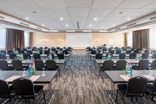 a conference room with tables and chairs and a screen at Best Western Plus Plaza Hotel Darmstadt in Darmstadt