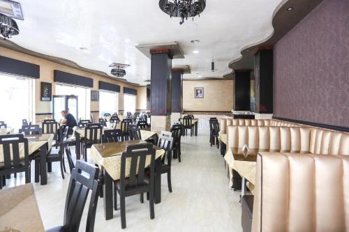 a dining room with tables and chairs and a person in the background at Hôtel Suite Martil in Martil