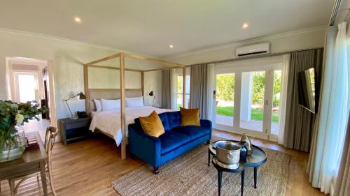 een grote slaapkamer met een bed en een blauwe stoel bij La Paris Estate in Franschhoek