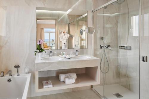 a white bathroom with a sink and a shower at La Réserve de Beaulieu in Beaulieu-sur-Mer