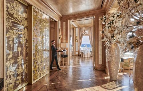 a man in a suit standing in a hallway with paintings at La Réserve de Beaulieu in Beaulieu-sur-Mer