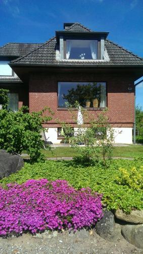 dom z fioletowymi kwiatami przed nim w obiekcie Haus OstseeLicht w mieście Sierksdorf