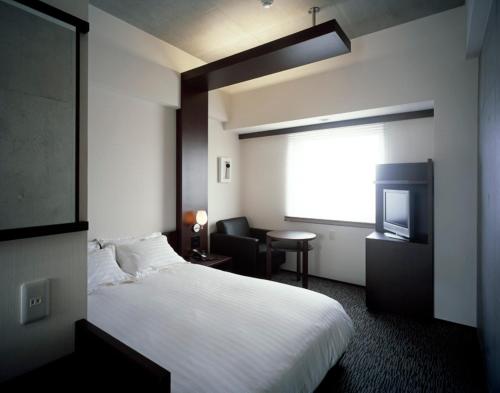 a hotel room with a bed and a television at Furano Natulux Hotel in Furano