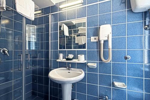 ein blau gefliestes Bad mit einem Waschbecken und einer Dusche in der Unterkunft Hotel La Scaletta in Lido di Ostia