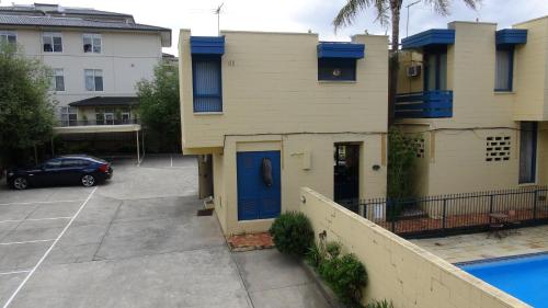 a house with a blue door next to a parking lot at Pathfinder Motel in Melbourne