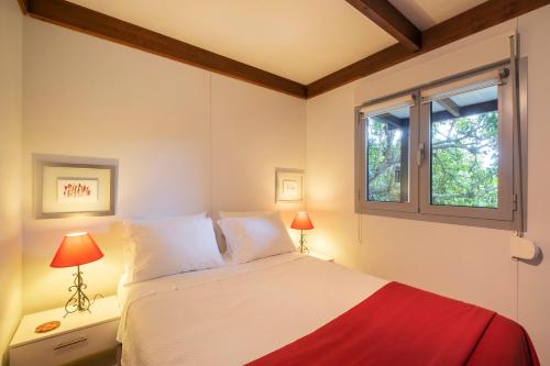 a bedroom with a bed with two lamps and a window at Casa das Clivias in Ponta Delgada