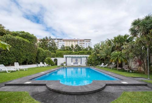 a swimming pool in a yard with a building in the background at Casa das Clivias in Ponta Delgada