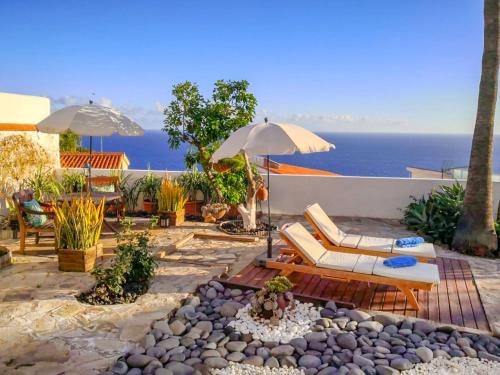 un patio con sillas y sombrillas y el océano en Apartment Antequera by Interhome, en Radazul