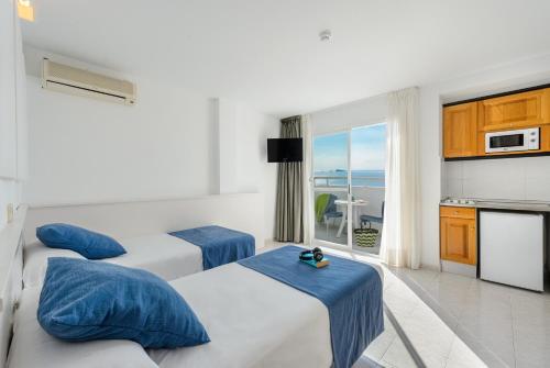 a hotel room with three beds and a balcony at Apartamentos Vibra Panoramic in Ibiza Town