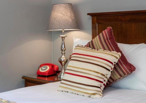 a bed with a pillow and a red alarm clock at Abbeyglen Castle Hotel in Clifden