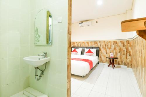 a bathroom with a bed and a sink in a room at OYO 2580 Hotel Puri Royan in Denpasar