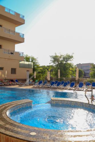 a swimming pool with blue chairs in a hotel at Hotel Monarque Costa Narejos in Los Alcázares