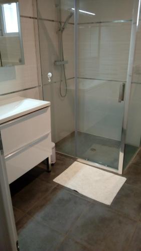 a bathroom with a glass shower and a sink at les tilleuls in Léon