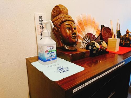 a table with a bottle of lotion and a statue at Guesthouse Hajimari in Kashihara