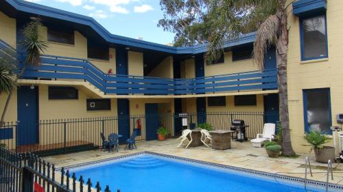 a house with a swimming pool and a blue sky at Pathfinder Motel in Melbourne