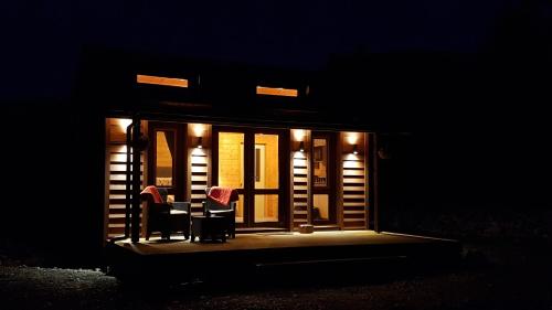 a room with two chairs and a table at night at Cosy Cabin in the Paddocks - Breakfast Included in Franz Josef