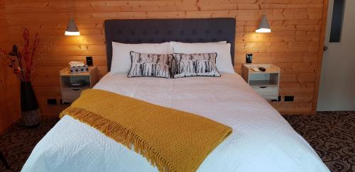 a bedroom with a large white bed with two pillows at Cosy Cabin in the Paddocks - Breakfast Included in Franz Josef