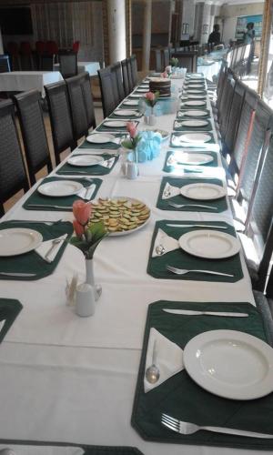 a long table with green and white plates and napkins at Lajava Guest Lodge in Krugersdorp