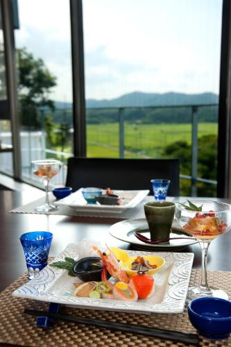 a table with two plates of food and wine glasses at Resort Hills Toyohama Soranokaze in Toba