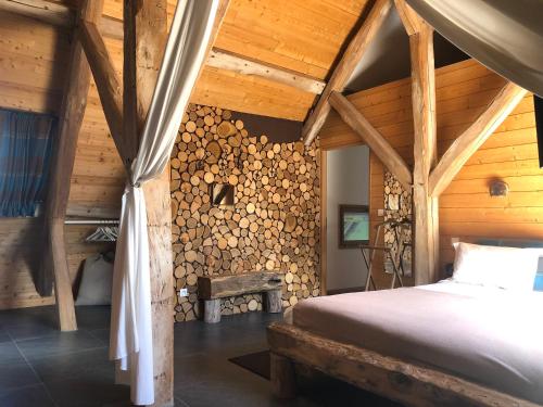 a bedroom with a bed and a wall of logs at La Ferme des Isles in Authouillet