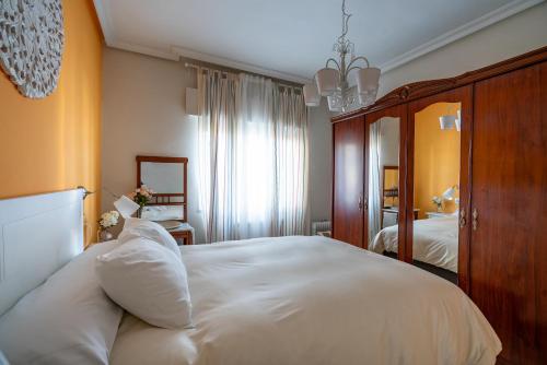 1 dormitorio con 1 cama blanca grande y espejo en Casa Angel, en Cáceres