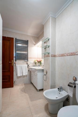 a white bathroom with a sink and a toilet at Casa Angel in Cáceres