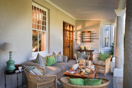 a porch with a couch and chairs and a table at Kwandwe Uplands Homestead in Grahamstown