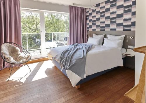 a bedroom with a bed and a window and a chair at Just Eleven in Sankt Peter-Ording