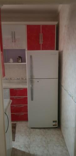 una nevera blanca en una cocina con armarios rojos en mody appartment at alexandria en Alexandría
