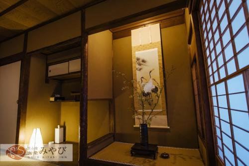 a room with a vase and a painting on the wall at Gojo Miyabi Inn in Kyoto