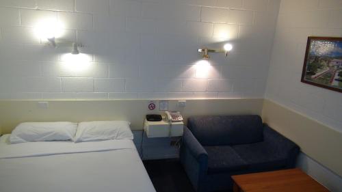 Habitación pequeña con cama y sofá en Pathfinder Motel, en Melbourne