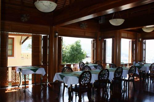 a dining room with tables and chairs and large windows at Prince Edouard Apartments & Resort Patong Beach Phuket in Patong Beach