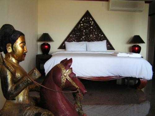 a bedroom with a bed with a statue next to it at Prince Edouard Apartments & Resort Patong Beach Phuket in Patong Beach