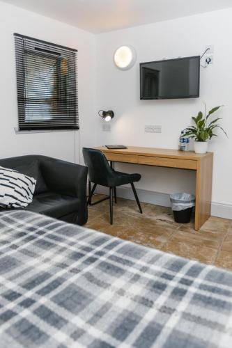 a bedroom with a desk and a chair and a television at Siberia Bar & Hotel in Aberdeen