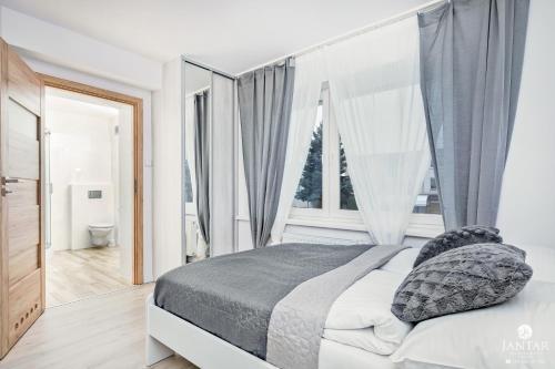 a bedroom with a bed and a large window at Jantar Apartamenty - Willa Jałowcowa in Grzybowo