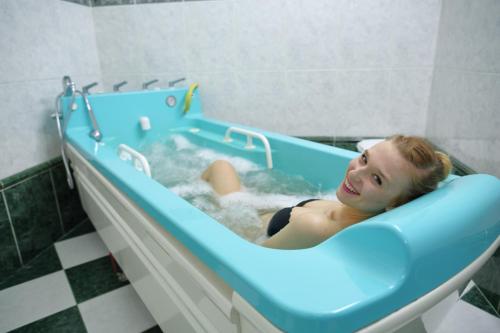 a woman is sitting in a bath tub at Schlosshotel Marienbad in Mariánské Lázně
