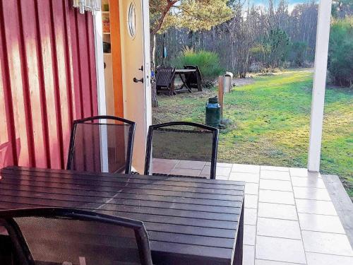 una mesa de madera y 2 sillas en el porche en 4 person holiday home in M nster s, en Mönsterås