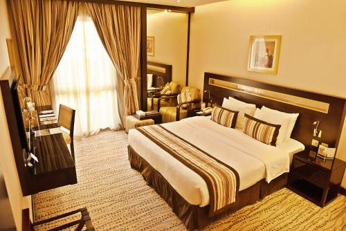 a hotel room with a large bed and a chair at Golden Tulip Bahrain in Manama