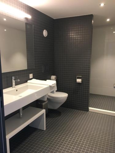 uma casa de banho com um lavatório, um WC e um espelho. em Tagungszentrum & Hotel evangelische Akademie Bad Boll em Göppingen