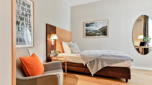 a small bedroom with a bed and a chair at BIO-Hotel Villa Orange in Frankfurt/Main
